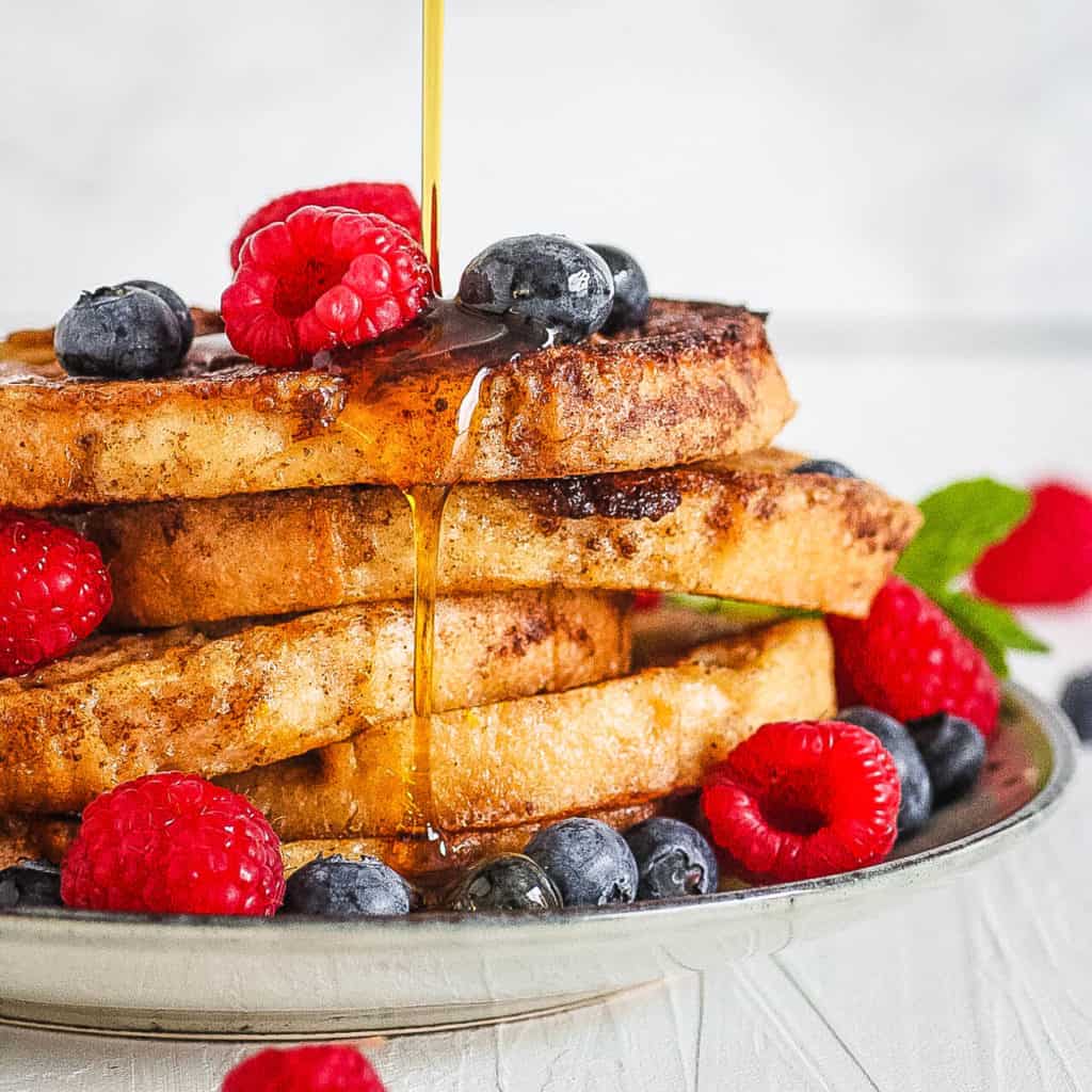 easy low calorie healthy french toast with berries and syrup served on a white plate