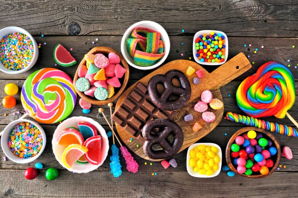 Colorful sweet low calorie candy buffet table scene. Above view over a rustic wood background.