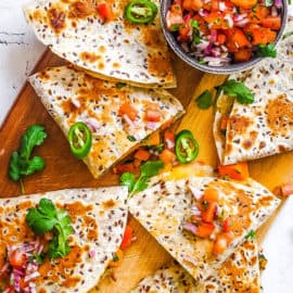 vegan quesadillas made with butternut squash and kale topped with pico de gallo on a cutting board