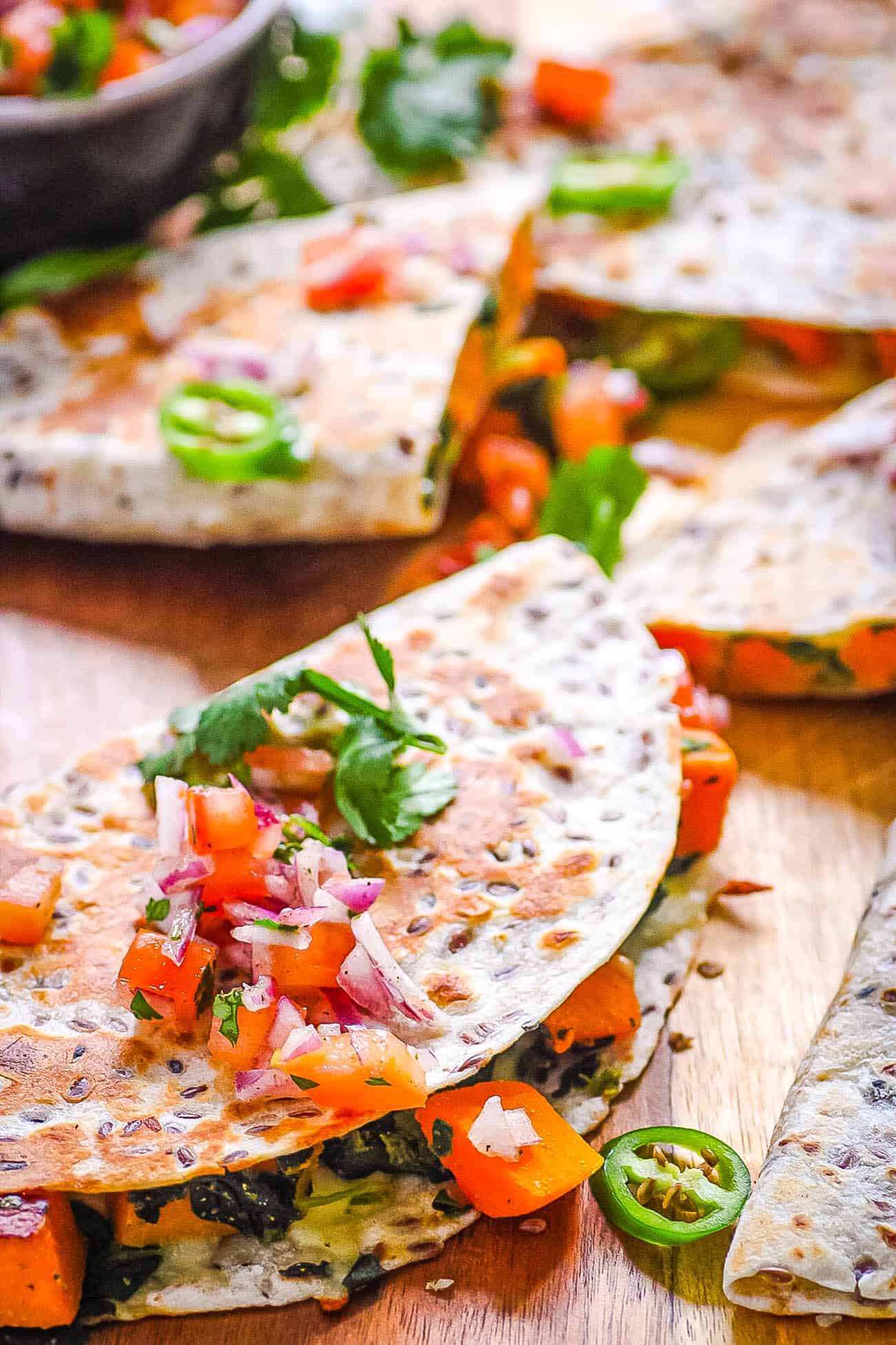 vegan quesadillas made with butternut squash and kale topped with pico de gallo on a cutting board