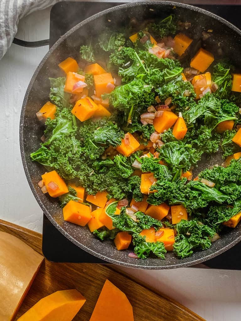 butternut squash and kale sauteeing in a pan