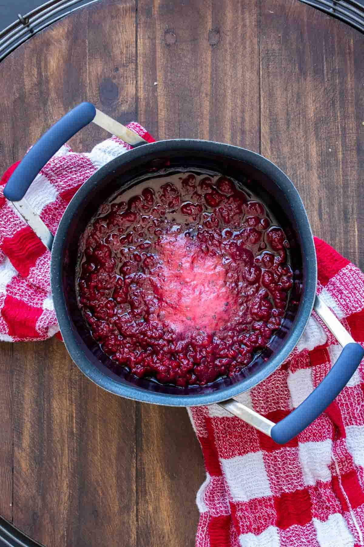 Overhead shot of chia seed jam in a pot with red checkered towel underneath.