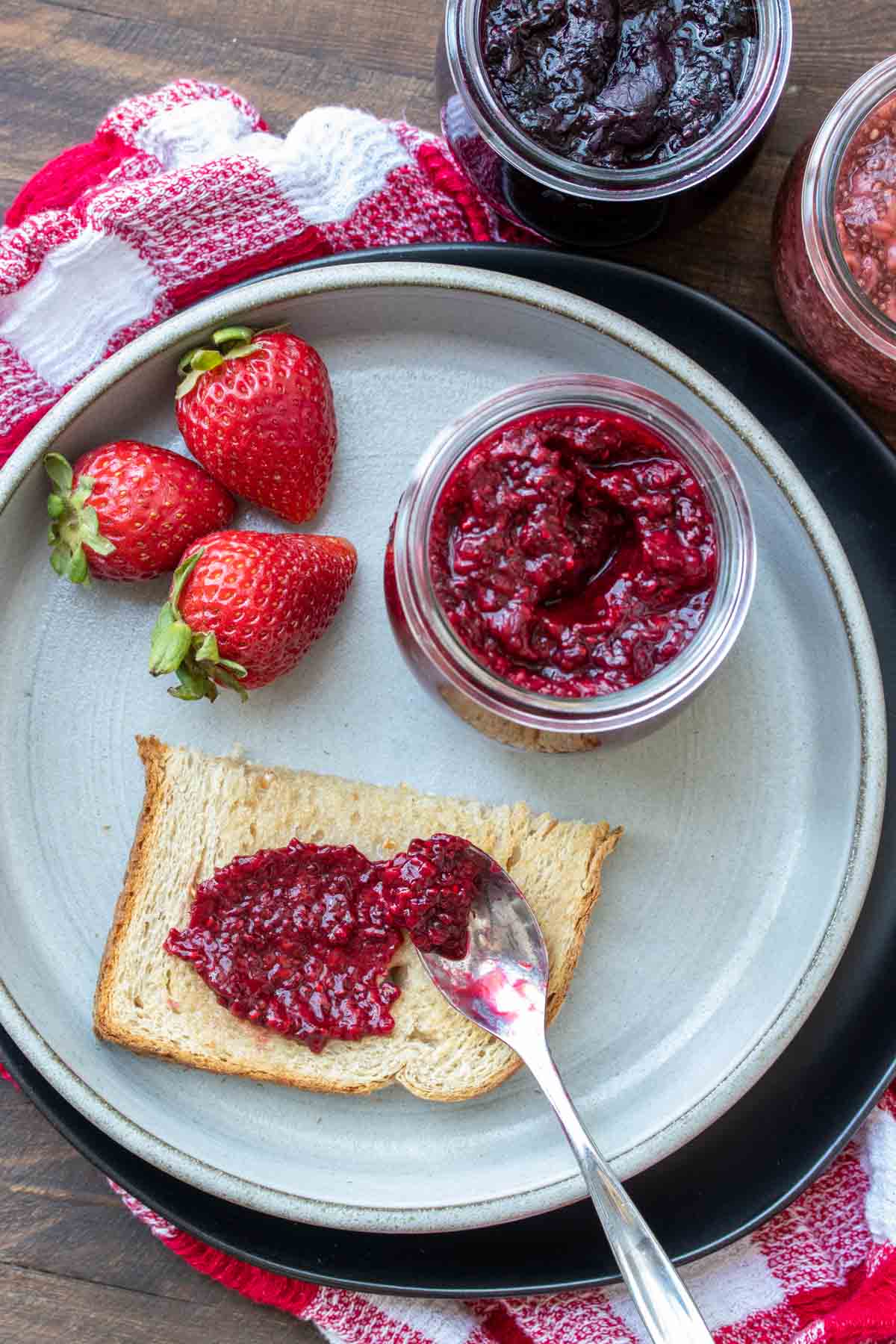 A plate with strawberries and chia seed jam spread onto a piece of toast.