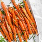easy delicious air fryer carrots served with fresh herbs on a white plate