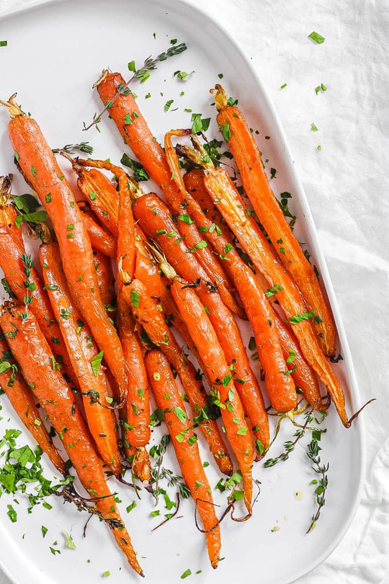 easy delicious air fryer carrots served with fresh herbs on a white plate