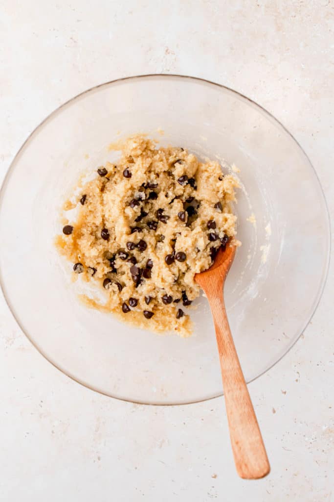 chocolate chips added to healthy edible cookie dough in a mixing bowl