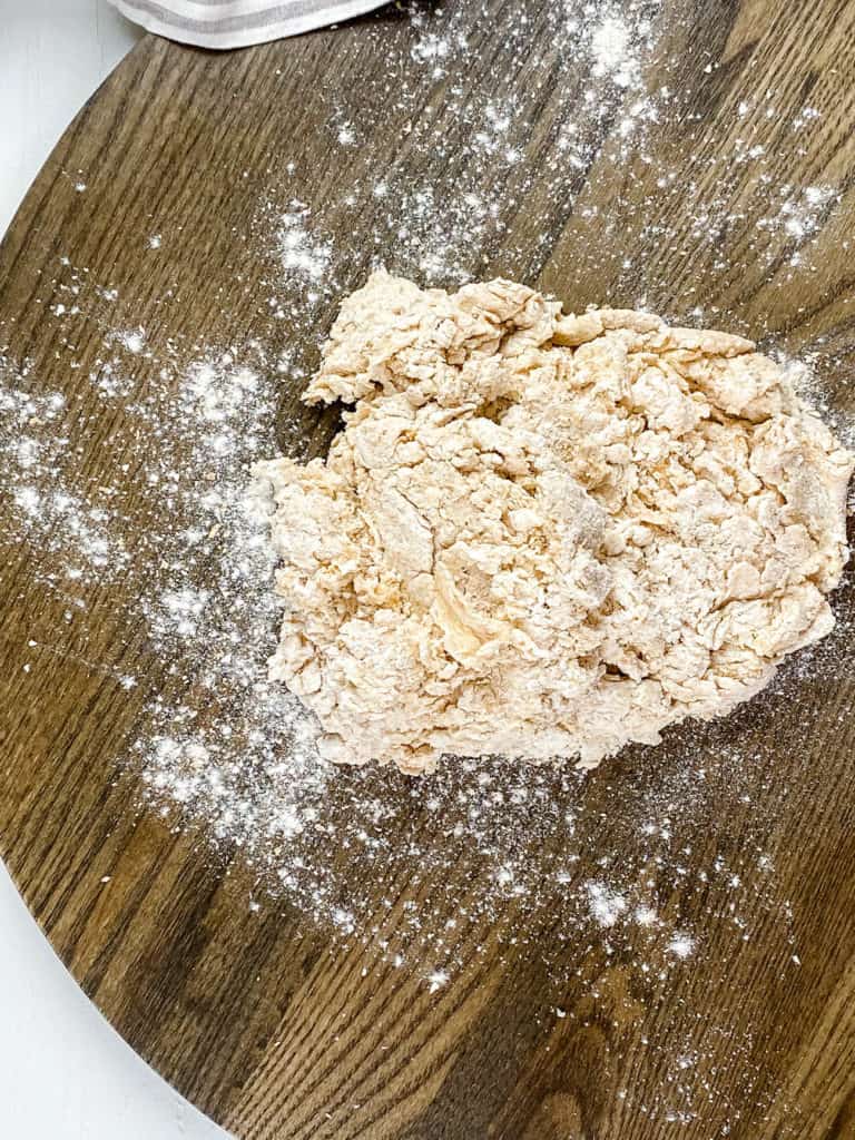 Pizza dough being formed on a cutting board. 