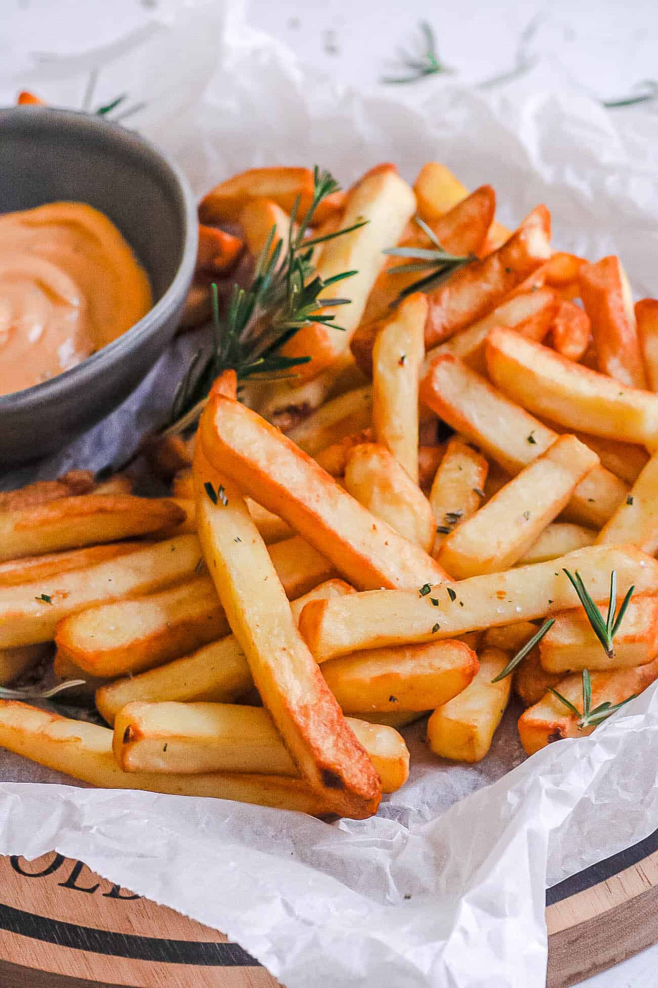 frozen french fries made in the air fryer on a plate with ketchup and rosemary
