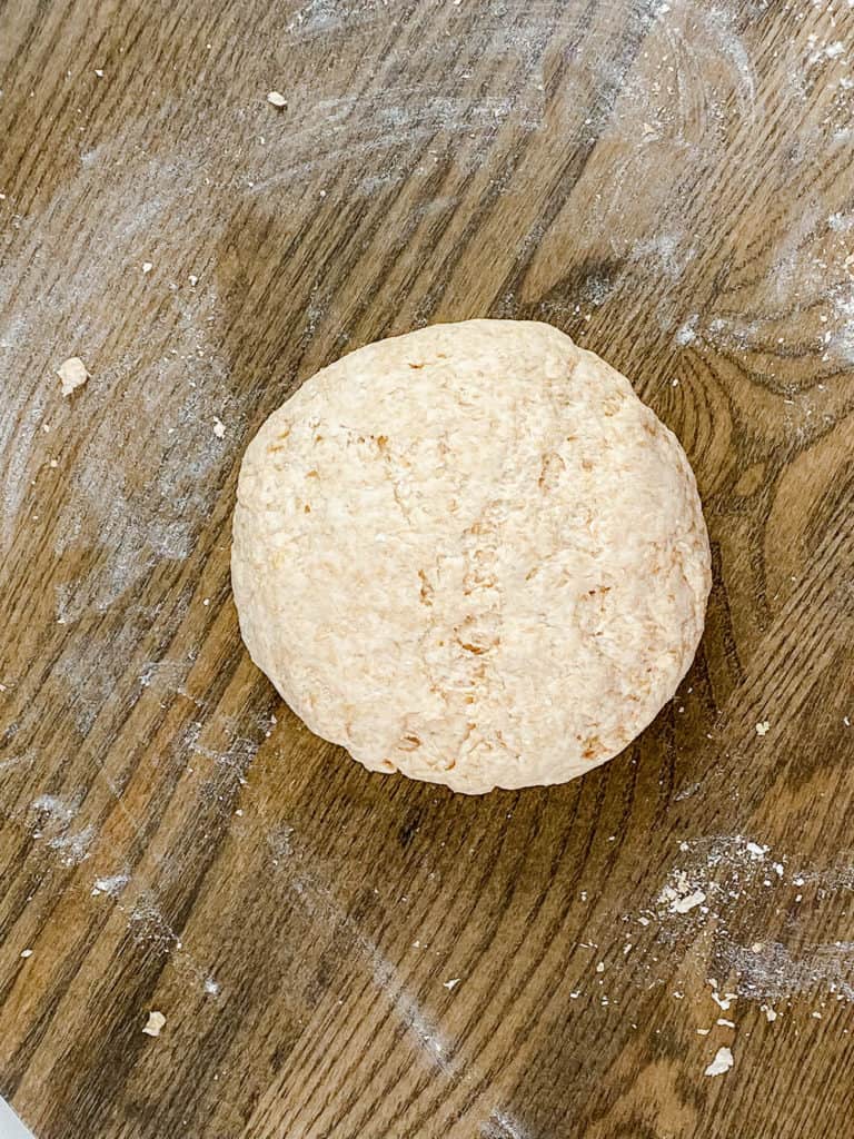 A ball of pizza dough on a cutting board.