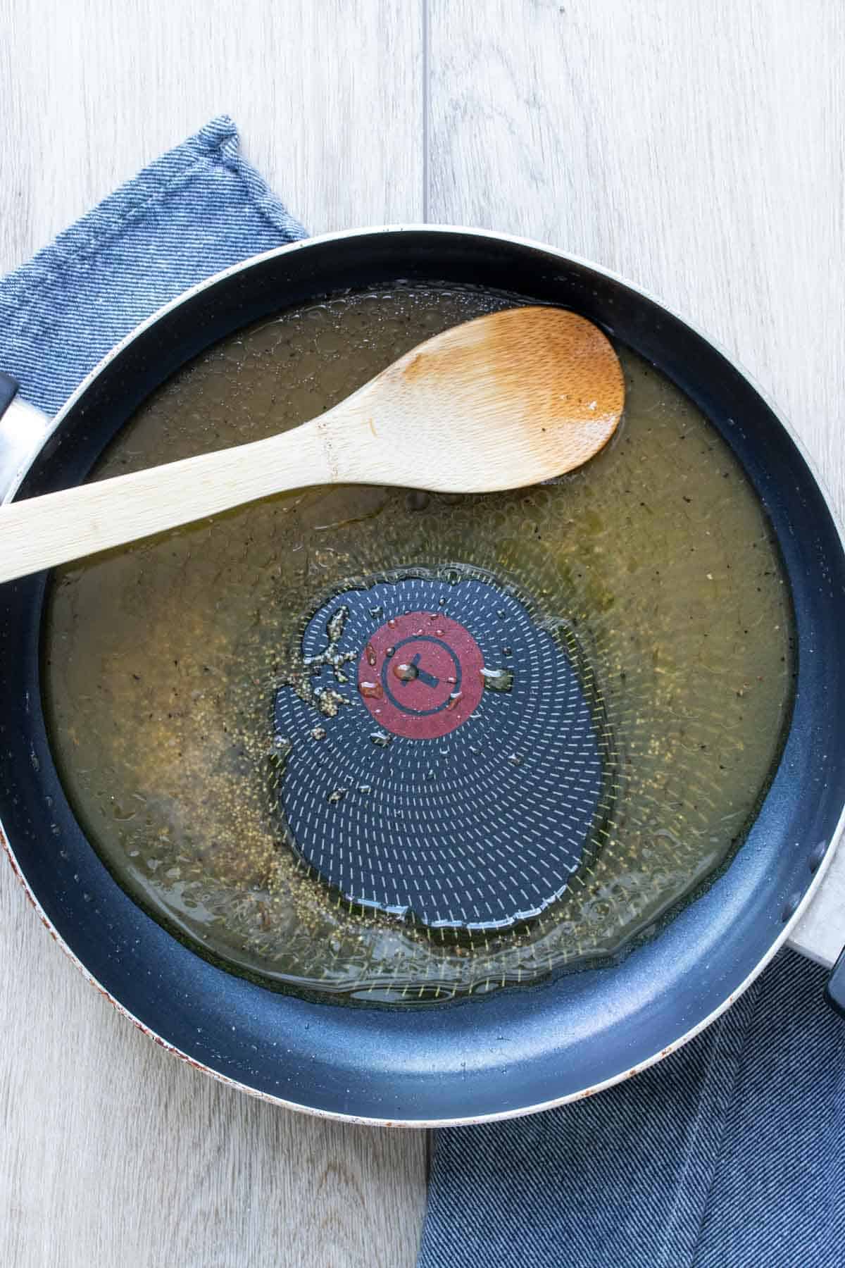 Wooden spoon mixing veggie broth in a saute pan.