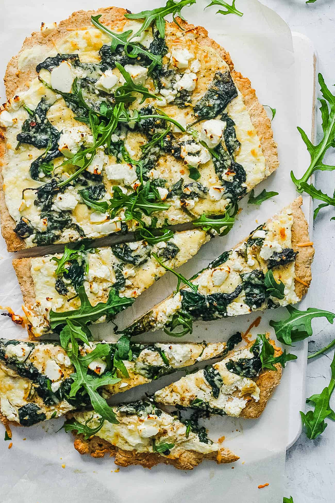 vegetarian florentine pizza - white pizza with spinach and parmesan cheese on a white platter