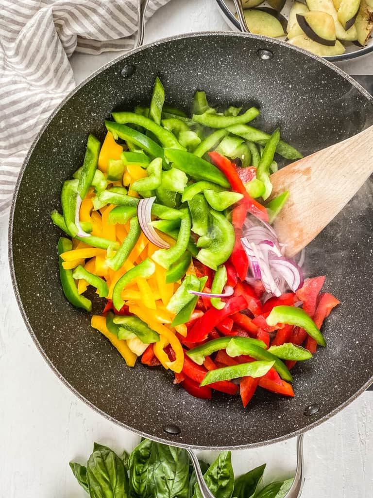 Onions and bell peppers cooking in a wok.