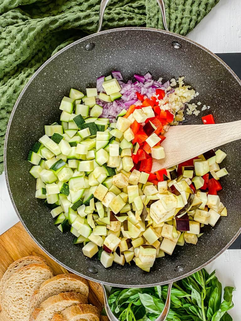 zucchini, eggplant, peppers and onions sauteeing in a pan
