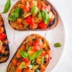 easy vegan bruschetta with tomatoes and white beans on a plate topped with basil