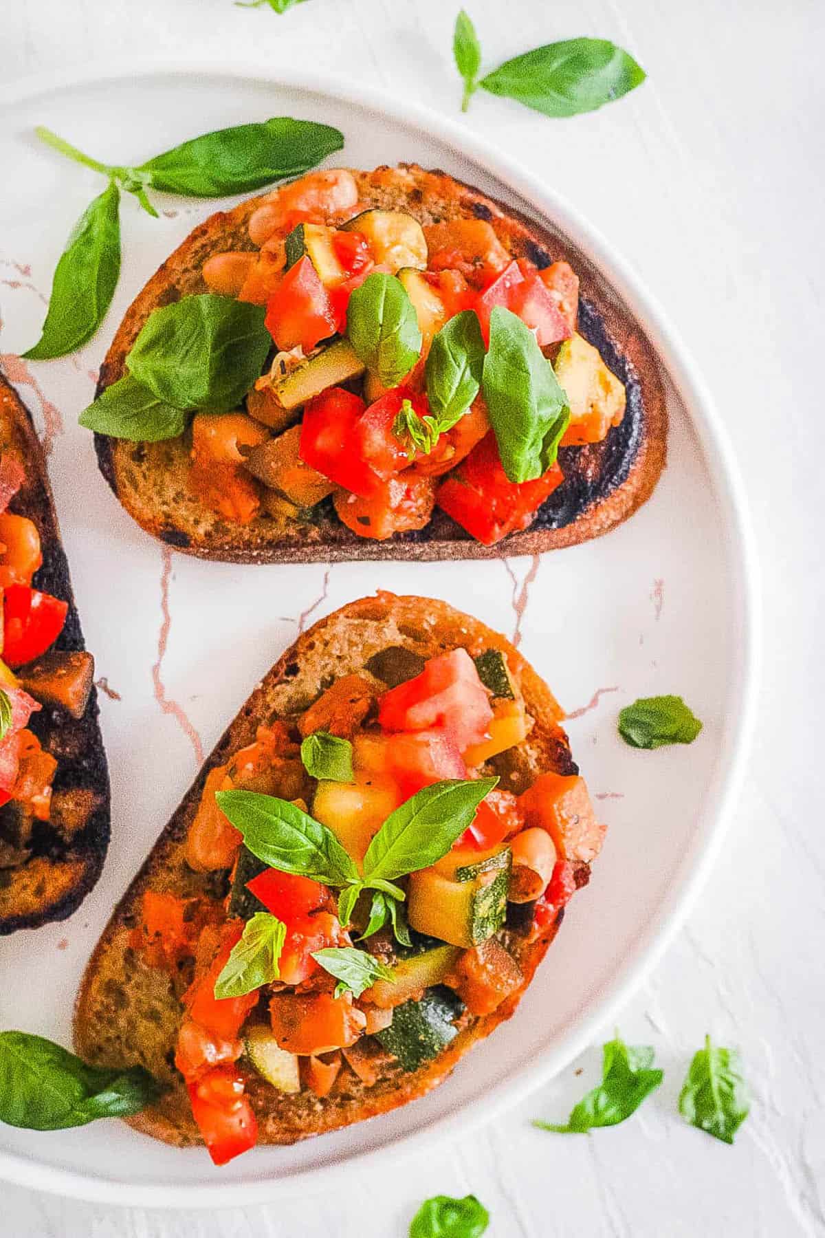 Easy vegan bruschetta with tomatoes and basil, served on a white plate.