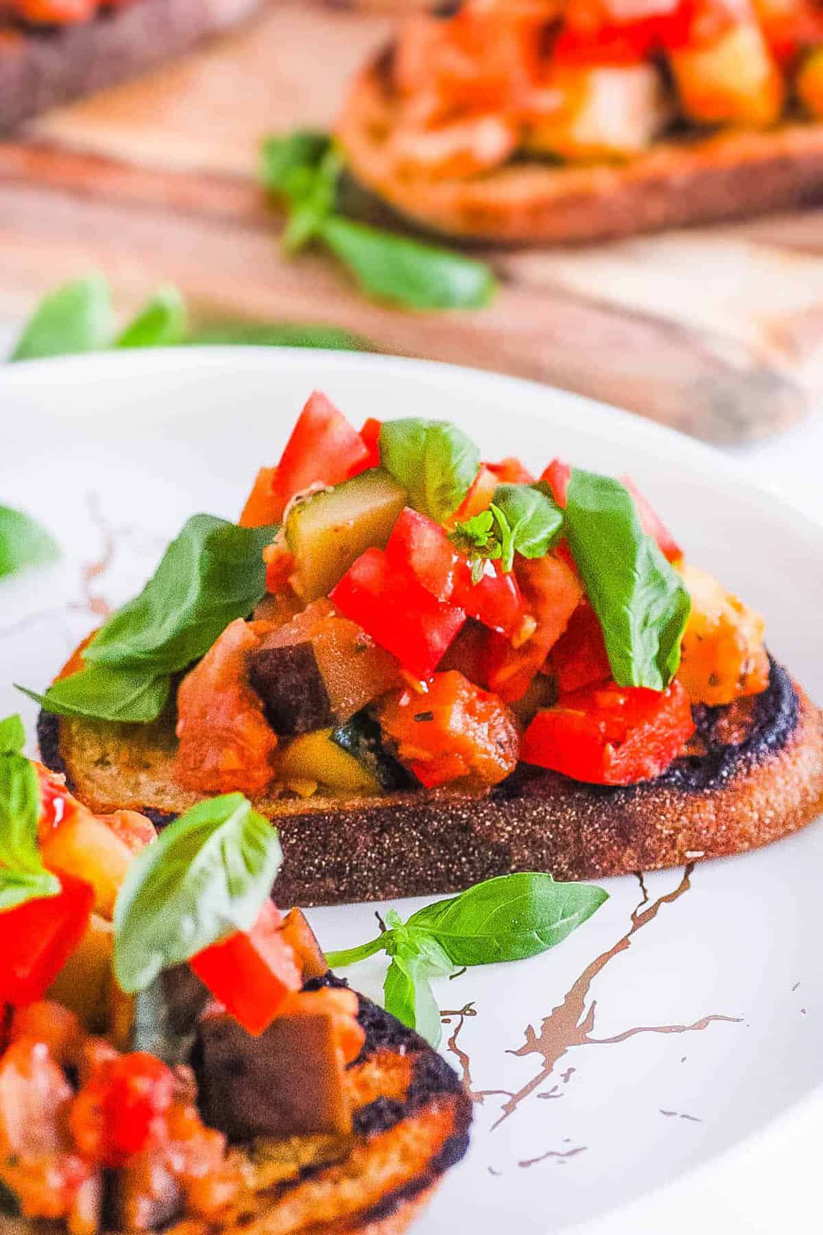 Vegan bruschetta with tomatoes and basil, served on a white plate.