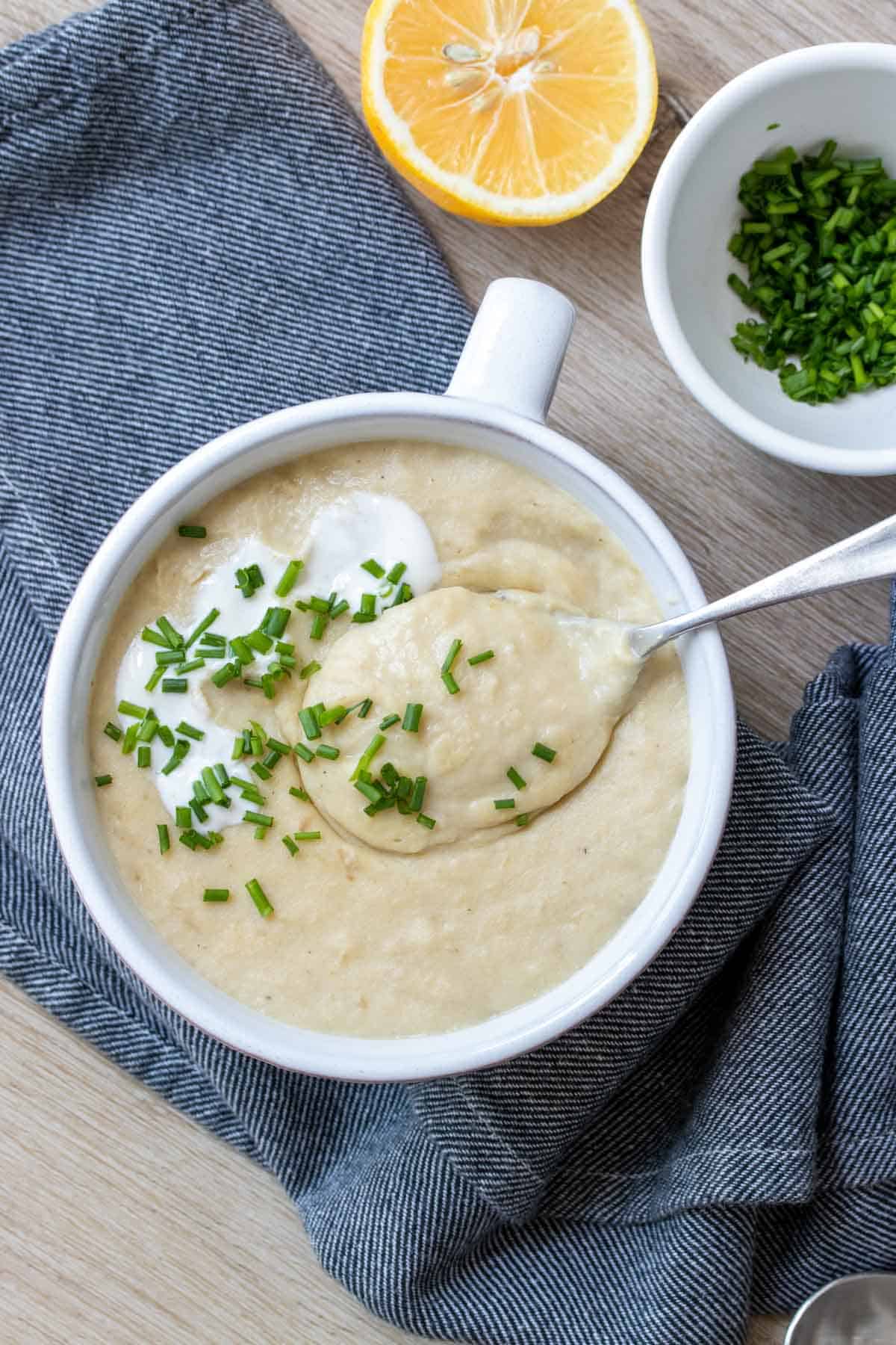 Spoon getting a scoop of a pureed soup from a white soup bowl