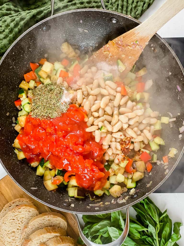 tomatoes white beans and veggies cooking in a pan