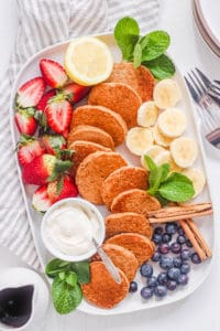 thick and fluffy mini pancakes - silver dollar pancakes recipe on a white plate with fresh fruit