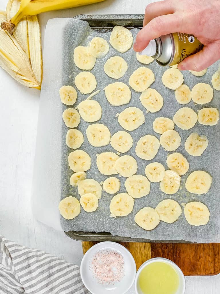 banana slices on a baking sheet sprayed with oil