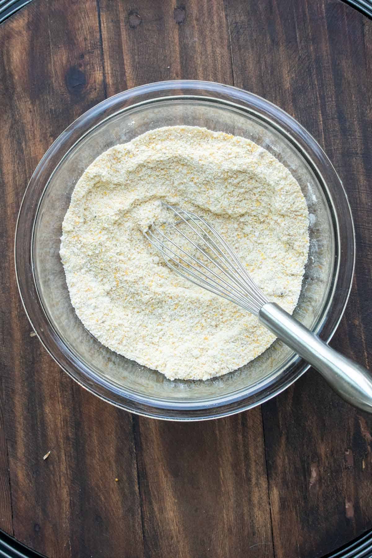 Whisk mixing flour and cornmeal in a glass bowl.