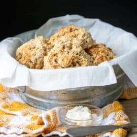 Vegan gluten free drop biscuits, displayed in a biscuit tin lined with a white cloth.