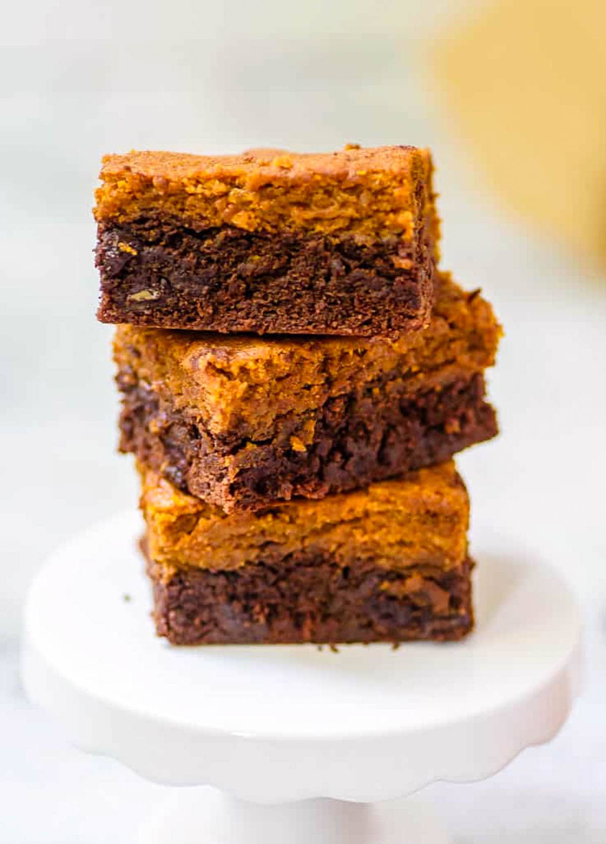 Healthy pumpkin brownies stacked on a white plate.