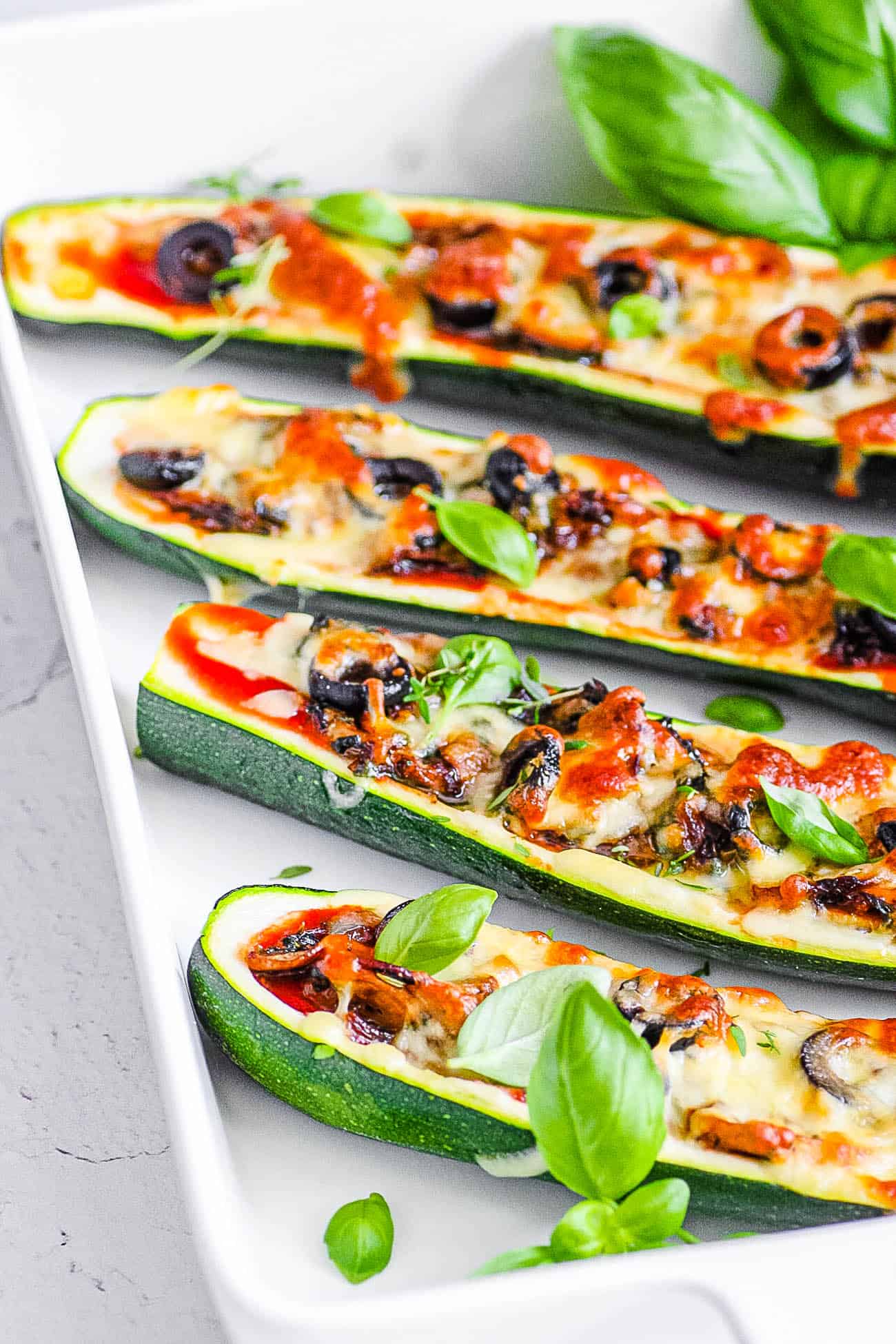 easy healthy vegetarian low carb zucchini pizza boats recipe on a white tray