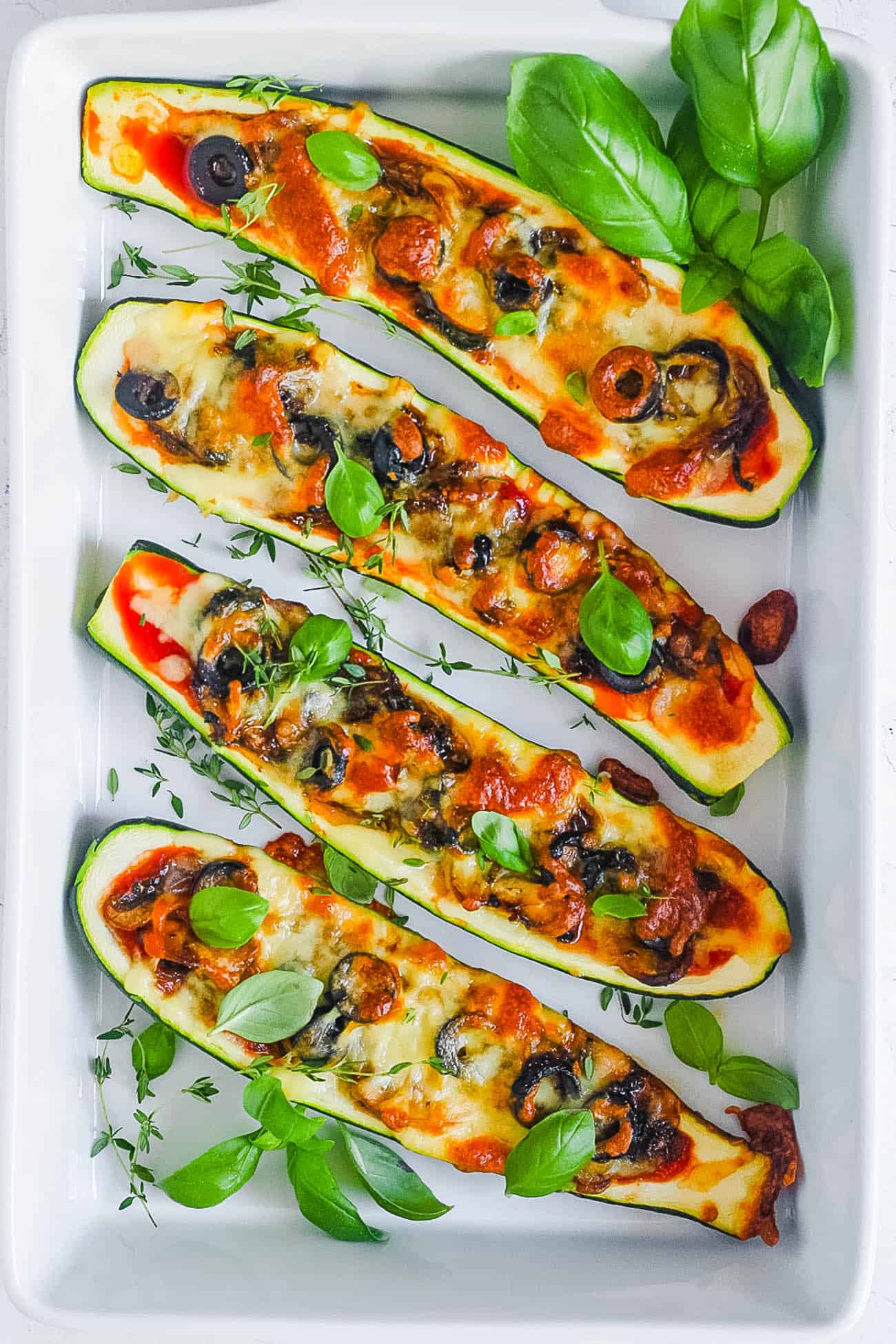 easy healthy vegetarian low carb zucchini pizza boats recipe on a white tray