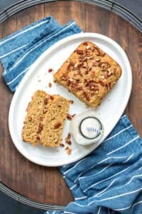 A white platter with slices of gluten-free dairy-free zucchini bread and a half loaf of the bread next to a jar of milk.