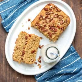 A white platter with slices of gluten-free dairy-free zucchini bread and a half loaf of the bread next to a jar of milk.