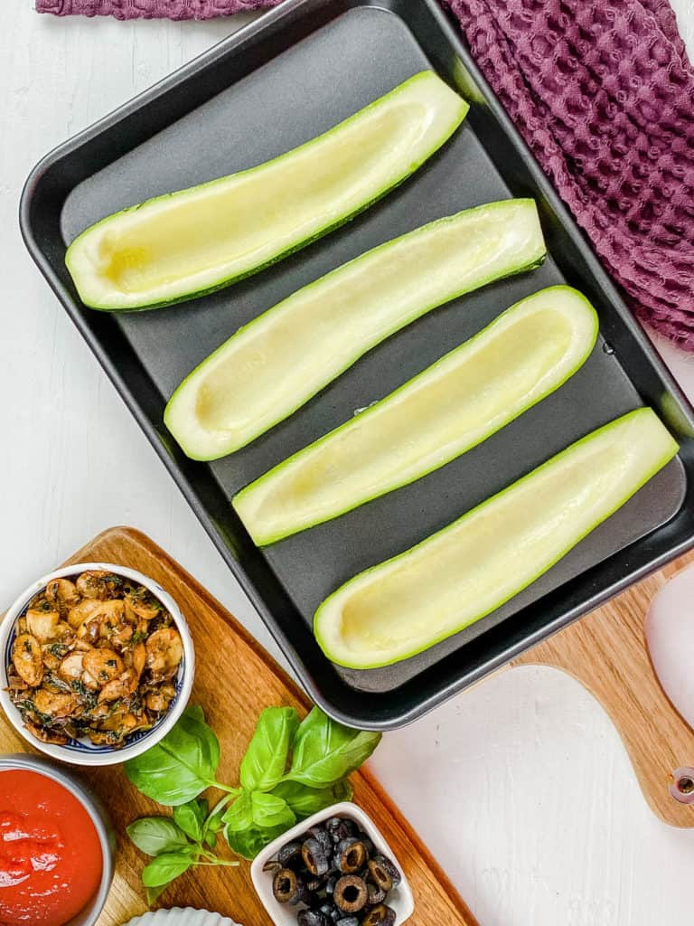 hollowed out zucchini on a baking sheet