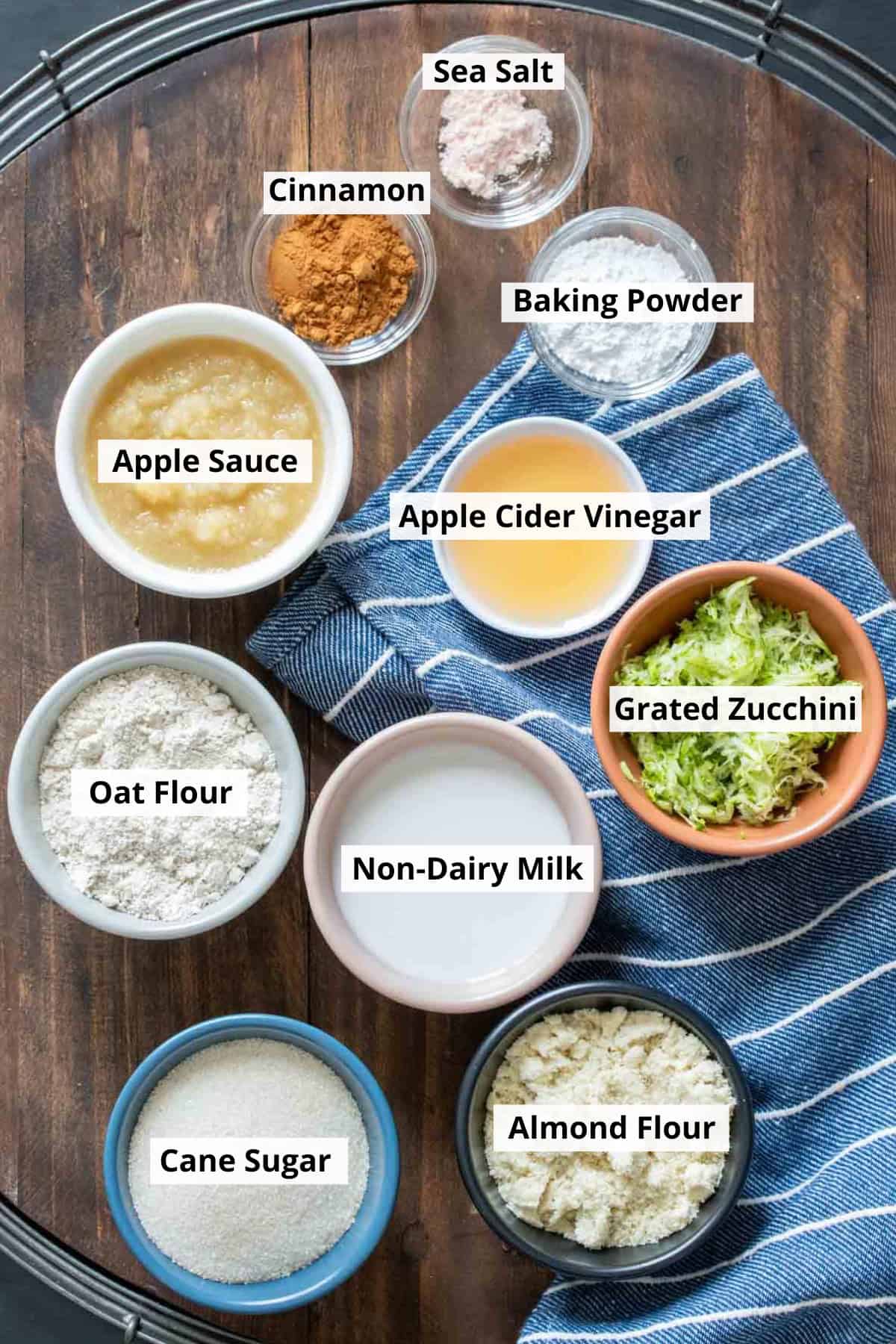 Bowls of ingredients needed to make a vegan zucchini bread on a wooden platter