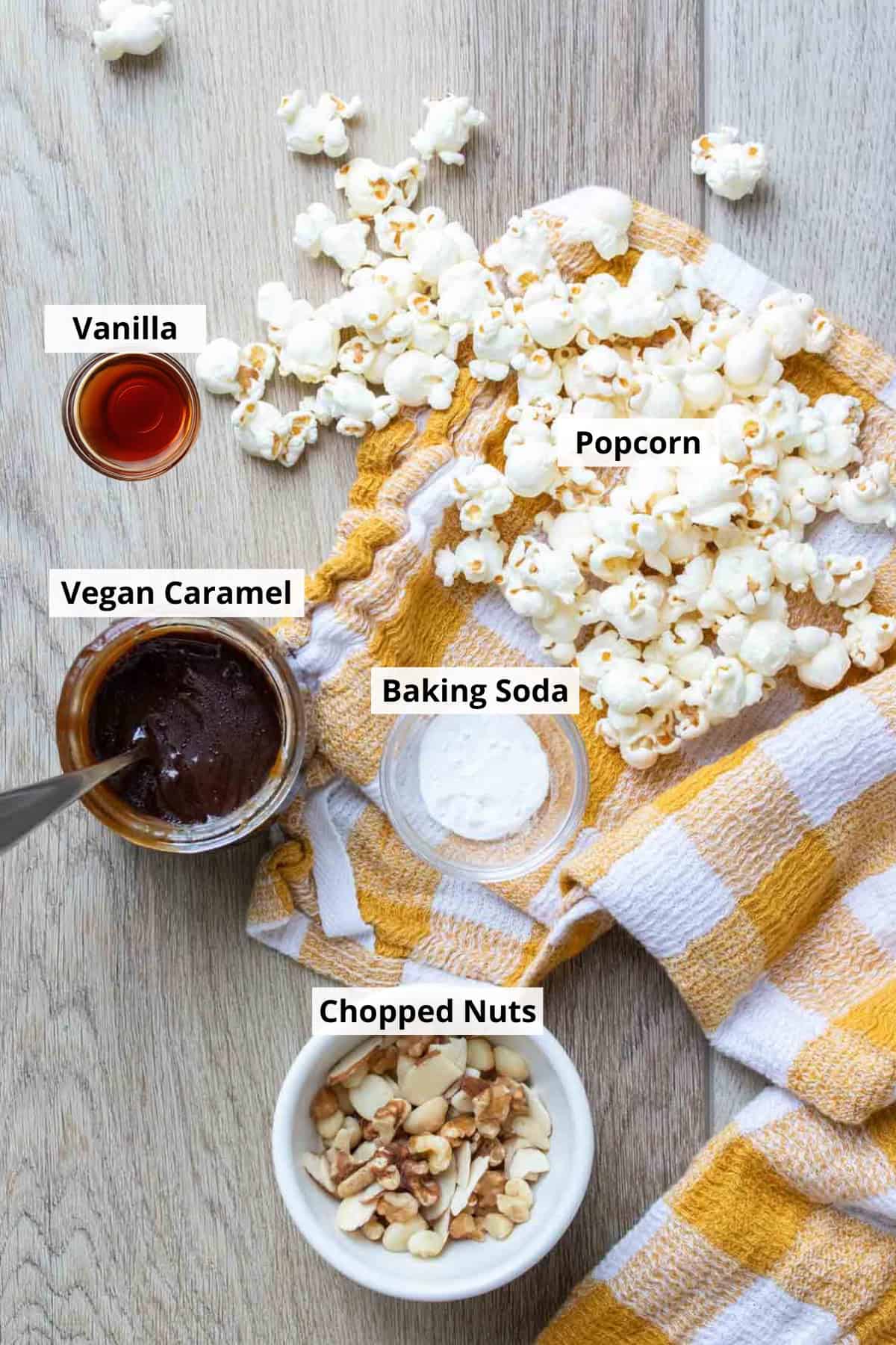 ingredients for caramel popcorn in separate bowls, with loose popcorn across a yellow checkered towel