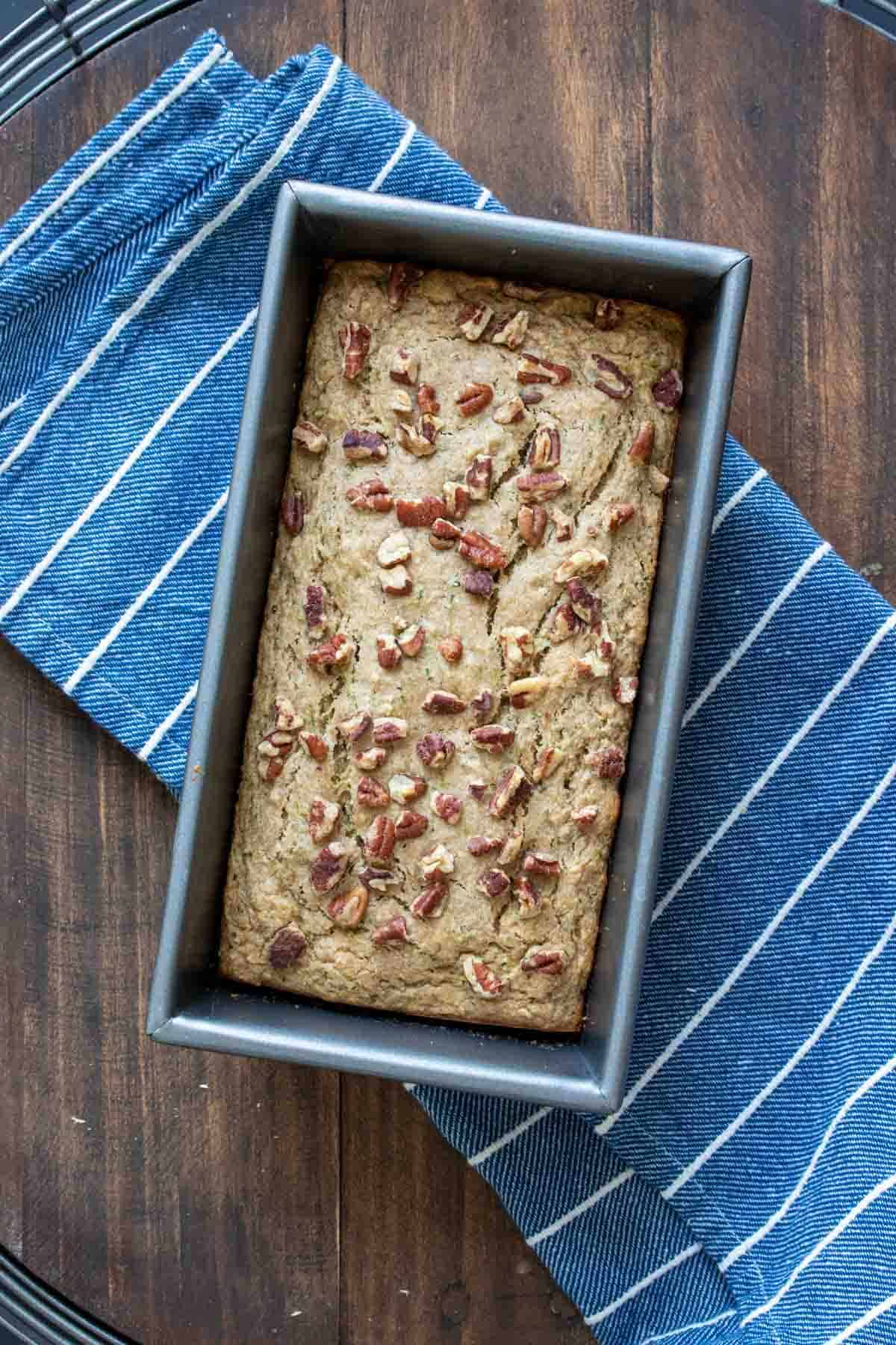 Baked zucchini bread in a baking dish with chopped nuts on top.