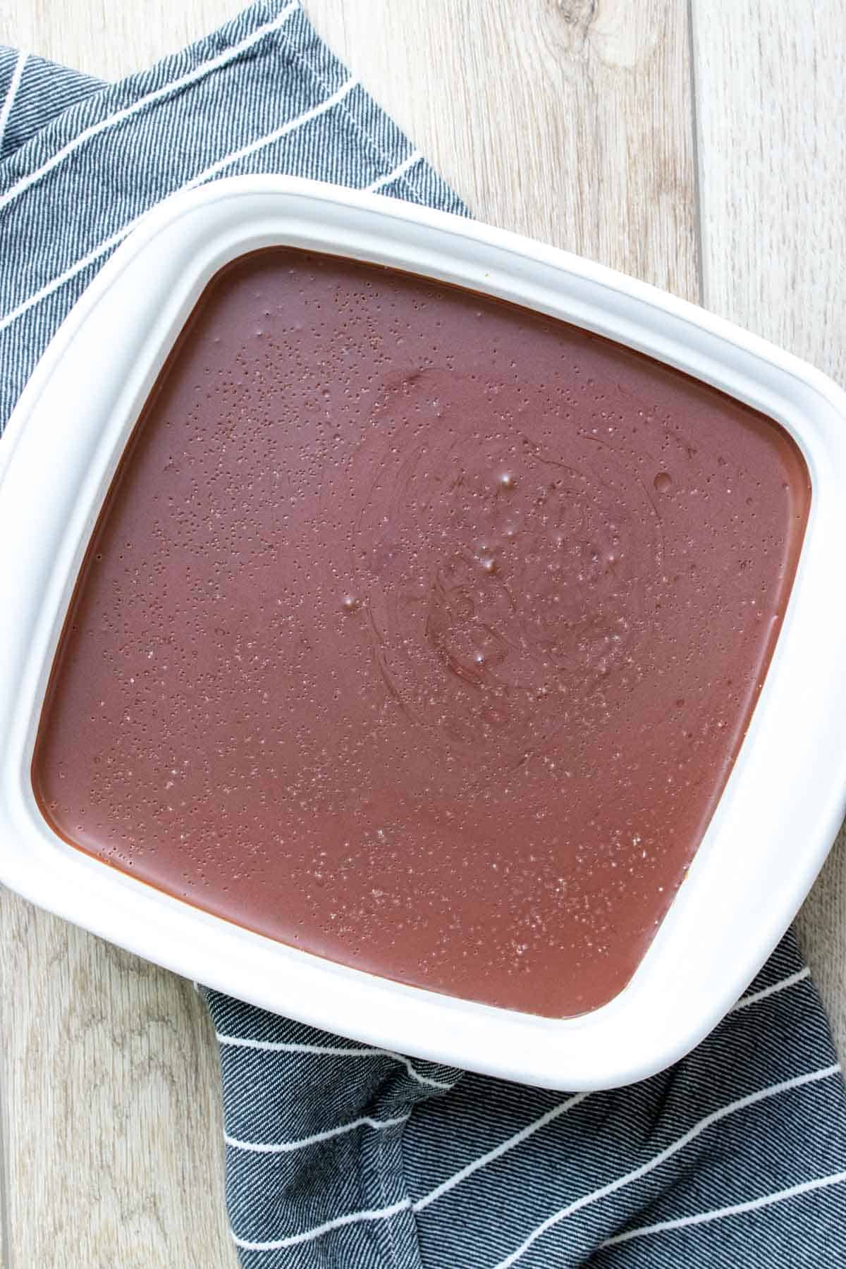 The top view of a square white baking dish with firm chocolate ganache in it.