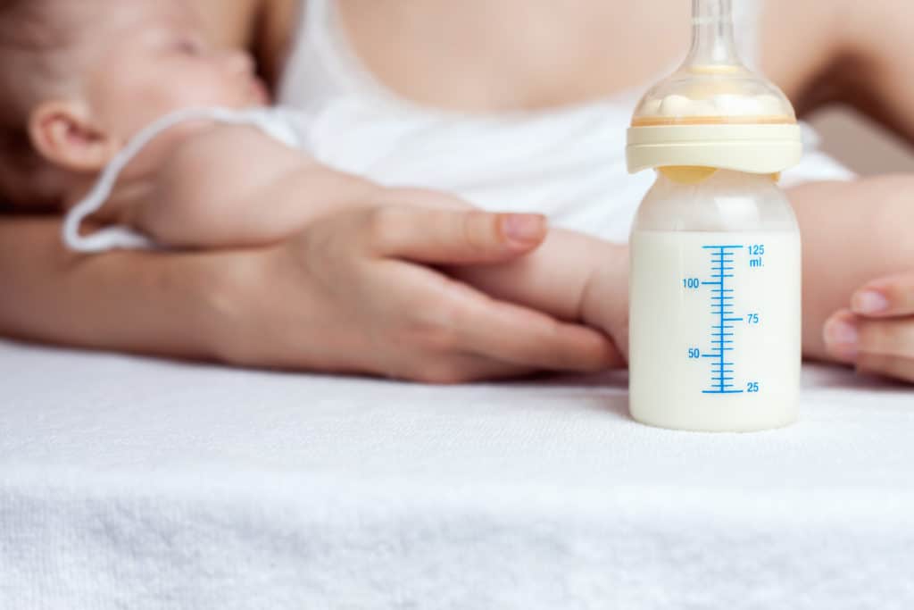 best goat milk baby formula - Mother holding a baby and bottle with breast milk for breastfeeding at foreground, mothers breast milk is the most healthy food for newborn baby