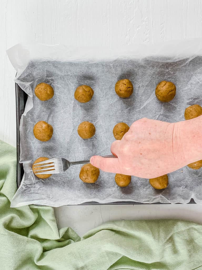 cookie dough balls pressed with a fork on a baking sheet