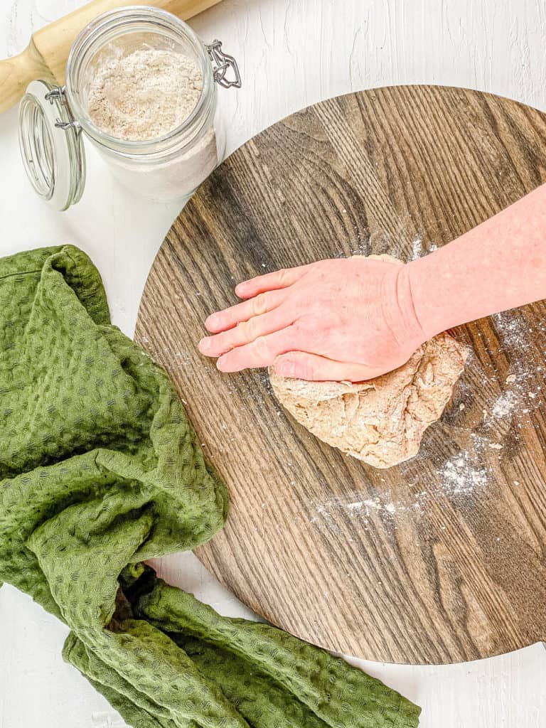 Kneading pizza dough on a wooden cutting board. 