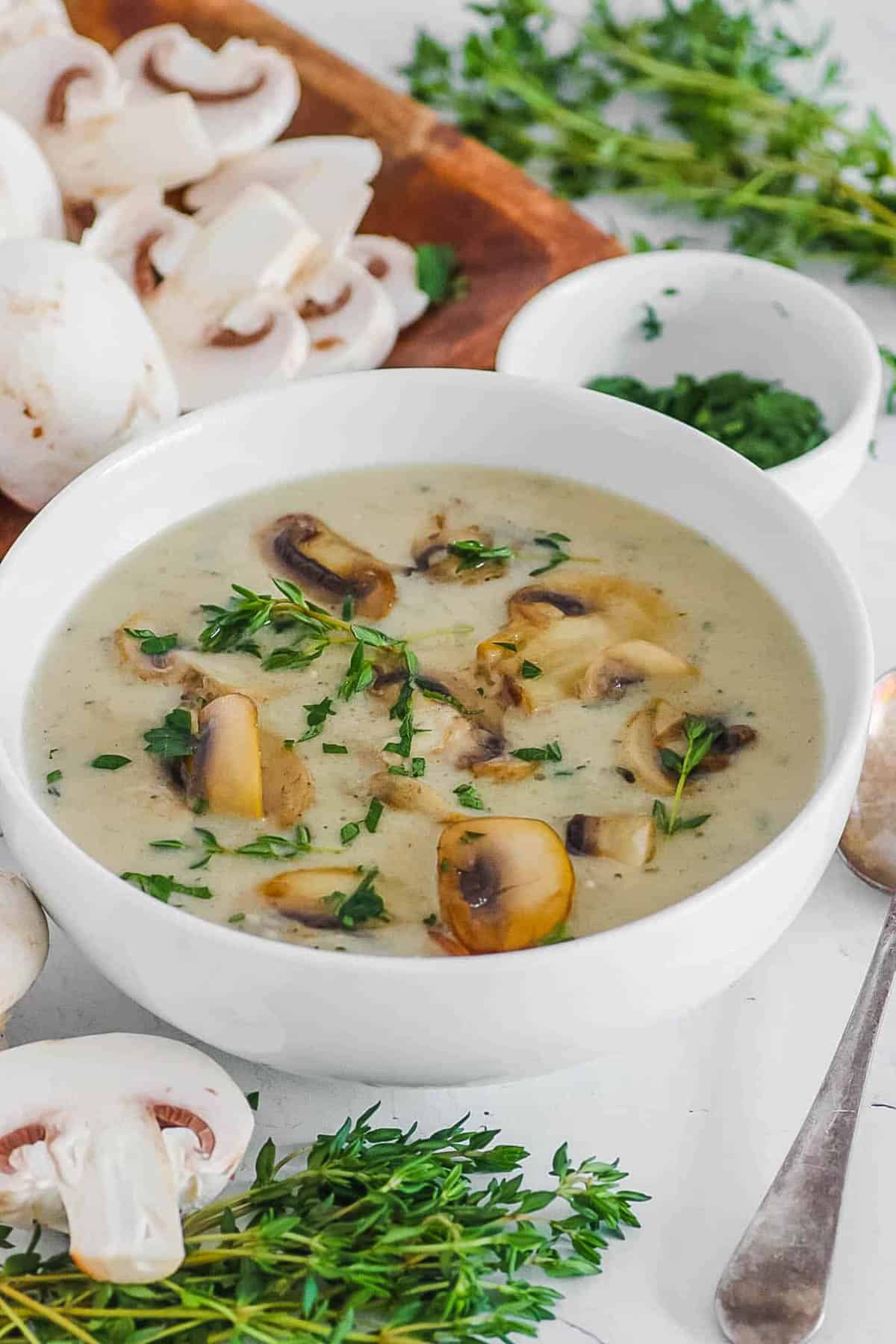 Healthy mushroom soup without cream in a white bowl, garnished with fresh herbs.