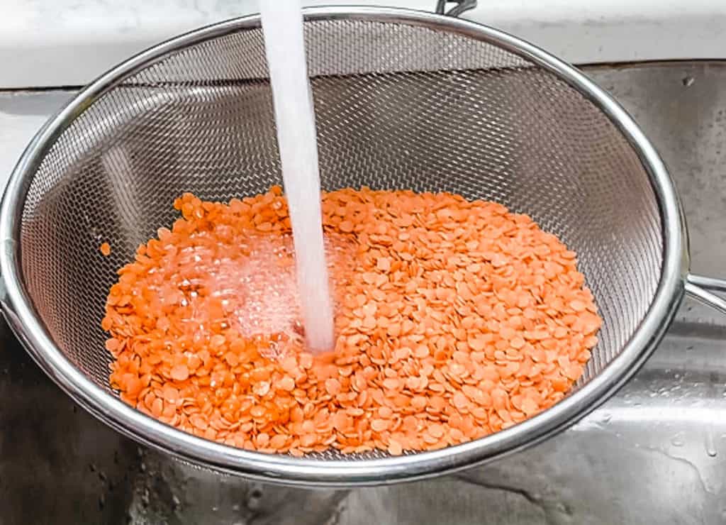 lentils being rinsed in a sink