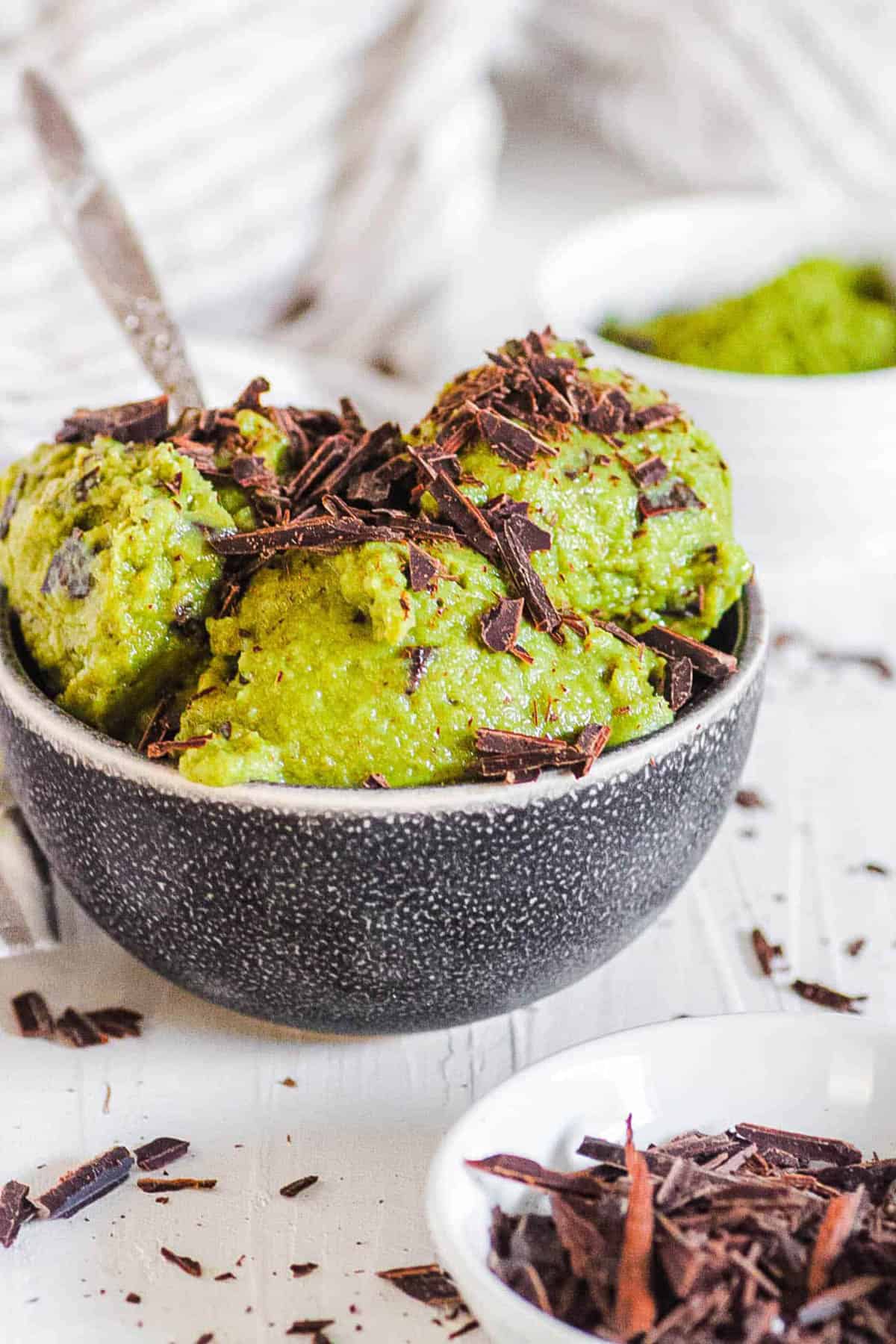 Homemade vegan matcha ice cream in a grey bowl with chocolate shavings.