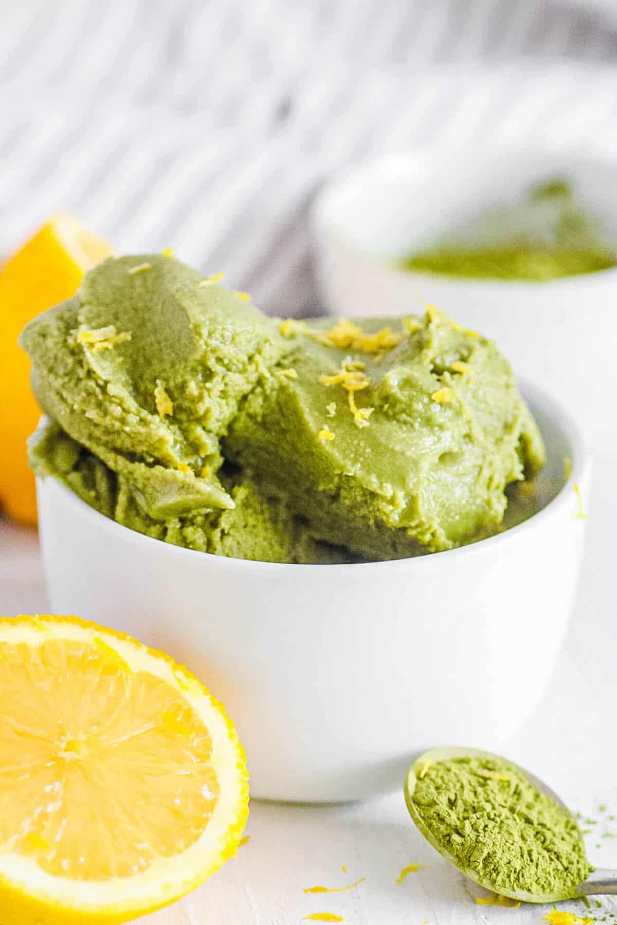 Homemade vegan matcha ice cream in a white bowl with lemon zest.