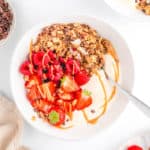 Overhead shot of a white bowl of a peanut butter bowl topped with peanut butter, berries, and granola.