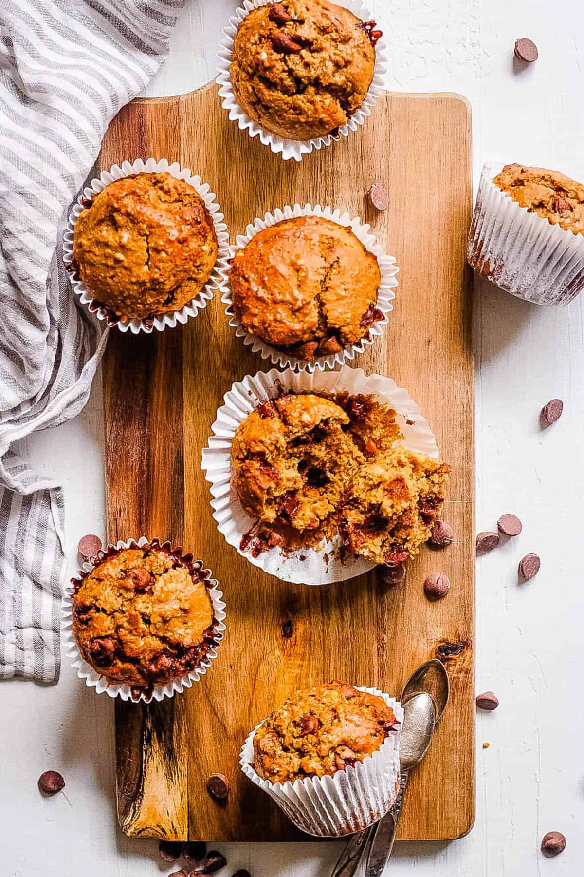 Healthy peanut butter muffins with chocolate chips on a wooden cutting board.