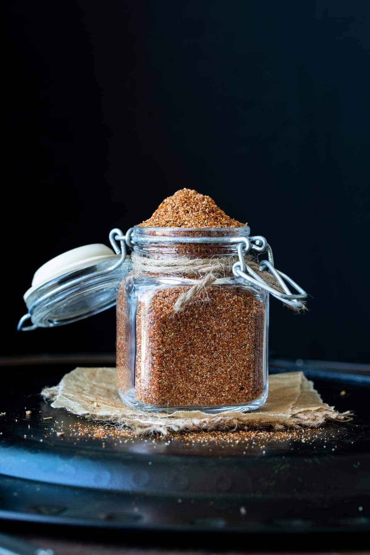 Use this amazing homemade taco seasoning for perfectly flavored tacos and so much more. You'll never guess the secret ingredient that adds unreal flavor! #veganmexicanrecipes #pantrystaples Front view of glass spice jar with clamp lid filled with homemade taco seasoning