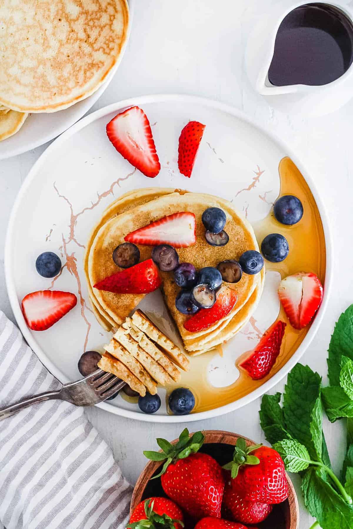 Japanese mochi pancakes served with maple syrup and berries on a white plate.