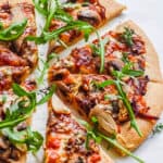 easy rustic pizza recipe with mushrooms and garlic cut into slices on parchment paper