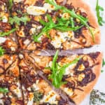 goat cheese pizza recipe with caramelized onions and arugula cut into slices