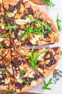 goat cheese pizza recipe with caramelized onions and arugula cut into slices